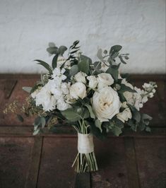 a bouquet of white flowers sitting on top of a wooden table