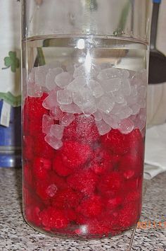 a glass jar filled with ice and red berries