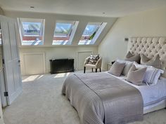 a large bed sitting under two windows next to a radiator in a bedroom