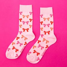 A pair of light pink socks with red, orange and pink bow patterns all over. Bow Socks, Foil Number Balloons, Garland Backdrops, Unicorn Valentine, Tiny Gifts, Sweets Gift, Birthday Badge, Holiday Bows, Bow Pattern