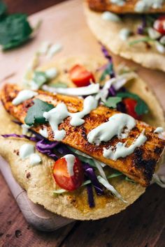 two pita breads topped with chicken, lettuce and tomatoes on a cutting board