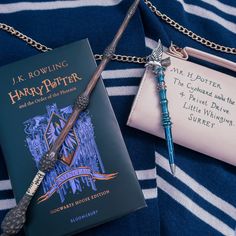 a harry potter book and wand on a blue and white striped blanket with a key chain attached to it