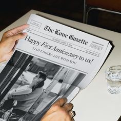 a person is holding up a newspaper on a table