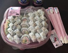 there is a plastic container filled with sushi rolls and two hello kitty napkins