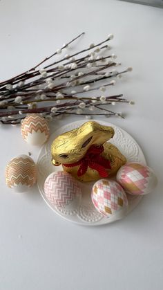 some eggs are sitting on a plate next to flowers and twigs in front of them