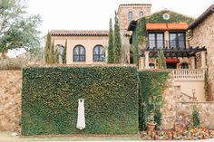 an old house with ivy growing on it's side and a white dress hanging in front