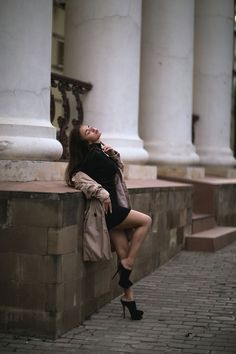 a woman leaning against a wall with her legs crossed