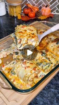 a casserole dish with spinach and cheese being spooned into the casserole