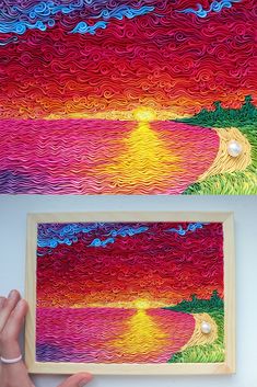 a person is holding up a piece of art that looks like the ocean and sunset