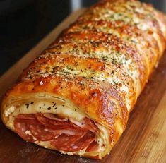 a ham and cheese roll sitting on top of a wooden cutting board