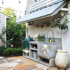 an outdoor kitchen is built into the side of a house with potted plants on it