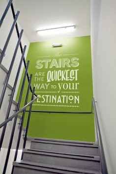 stairs leading up to the top of a green wall with white lettering on it that reads stairs are the quickest way to your destination