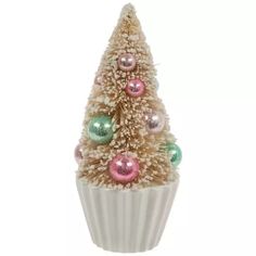 a small christmas tree in a white cupcake with pink and green ornaments on it