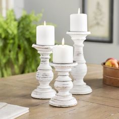 three white candles sitting on top of a wooden table