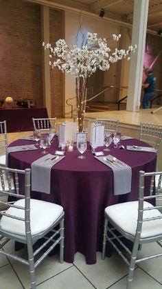 the table is set with purple linens and silver chairs