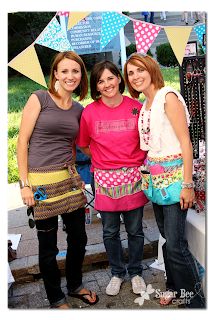 three women standing next to each other in front of a table with paper bunting