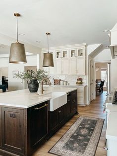 a large kitchen with an island in the middle and two pendant lights hanging from the ceiling