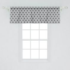 a window with a black and white pattern on the valance, next to a bed