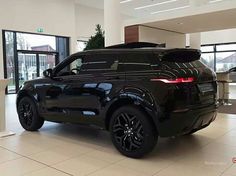 an suv is parked in the middle of a room with large windows and white tile flooring