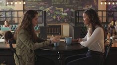 two women sitting at a table talking to each other