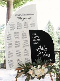 a seating chart with flowers and greenery sits on top of a wooden easel