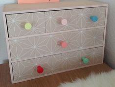 a white dresser with colorful knobs on it's drawers and a note attached to the drawer