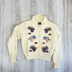 a white sweater with grapes and leaves on it