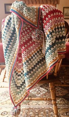 a crocheted blanket sitting on top of a wooden chair