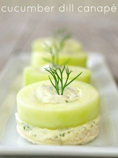 cucumber sandwiches with dill on top are served on a white platter