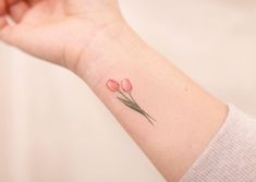 a small pink flower tattoo on the wrist