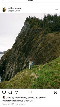 two people standing on top of a cliff next to the ocean