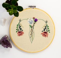 a close up of a embroidery on a white surface with a plant in the background