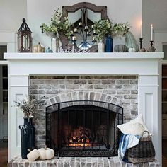 the fireplace is decorated with white pumpkins and greenery on it's mantle