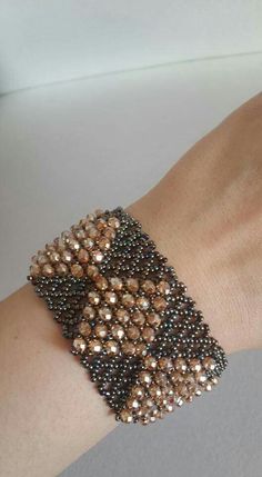 a woman's arm wearing a beaded bracelet with gold and black beads on it