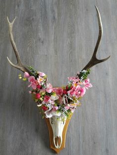 a deer's head decorated with flowers and antlers on a wooden flooring area