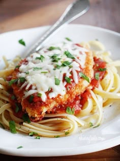 a white plate topped with pasta covered in sauce and parmesan