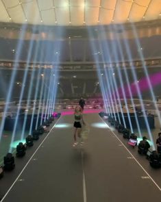 a man walking down a runway surrounded by lights