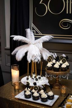 a table topped with cupcakes covered in white frosting and black icing