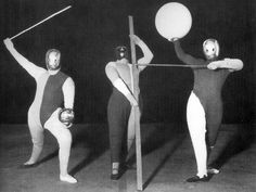 three women in bodysuits holding up large balls and poles while standing next to each other