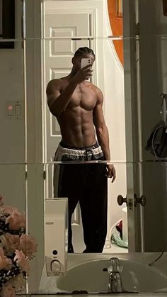 a shirtless man taking a selfie in front of a mirror with his cell phone