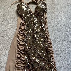 a brown dress with sequins on it laying on the floor next to a wall