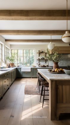 a large kitchen with wooden floors and white counter tops, along with an island in the middle