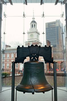 a large bell in front of a building with a clock tower