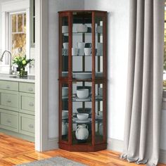 a corner cabinet with glass doors in the middle of a wooden floored kitchen area