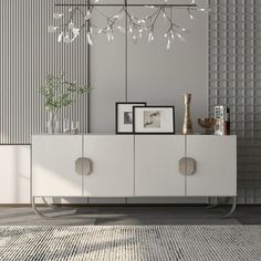 a white cabinet sitting next to a wall with framed pictures on it and a plant in the corner