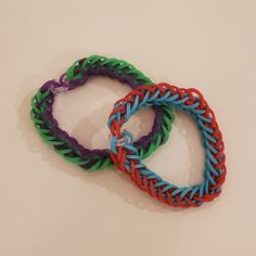 three different colored bracelets sitting on top of a white table next to each other