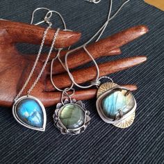 "Pendants of the collection ~NINFEA~ Stunning labradorite pieces, each of a different hue of colour ranging from deep blue to green and gold. The collection is inspired by water and by the beautiful plants and flower that grow into it, such as water lilies, \"nifea\" in Italian. All pieces are one of a kind and made with love. Here a full description of each piece: 1) Large piece of labradorite (3 x 2 cm) with green and golden hues set in a mix of silver and brass. The pendant is roughly 4.5 cm long and 3.5. cm wide. The back of the pendant features sun and cloud shaped cuts, thus showing the beauty of the stone from the back too. If desired, the pendant can be complemented by one of the two available types of chain. 2) Sleek pendant with a deep blue, tear-shaped labradorite piece. The pen Blue Labradorite Bohemian Jewelry, Bohemian Blue Labradorite Jewelry, Silver Brass Teardrop Necklace, Blue Labradorite Wire Wrapped Jewelry, Teardrop Shaped Silver Brass Necklace, Silver Nature-inspired Jewelry, Nature-inspired Silver Teardrop Jewelry, Spiritual Hand Forged Labradorite Jewelry, Fusion Style Wire Wrapped Pendant Jewelry