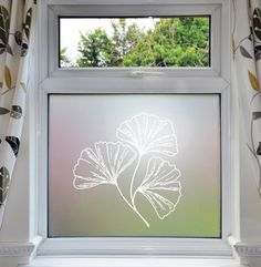 a window with a drawing of a leaf on the glass and trees in the background