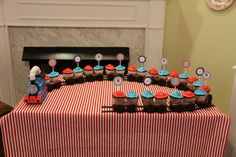 a table topped with cupcakes covered in frosting next to a fire place