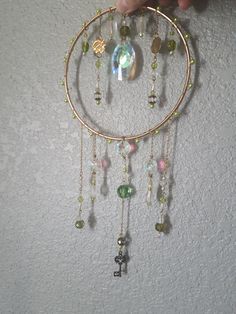 a person is holding up a gold hoop with beads and charms hanging from it's sides